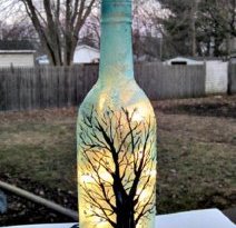 Прозрачную бутылку можно разрисовать акрилом,  такой простенький рисунок под силу даже начинающему художнику. Внутрь бутылки можно поместить гирлянду,  а можно — восковую свечу!
